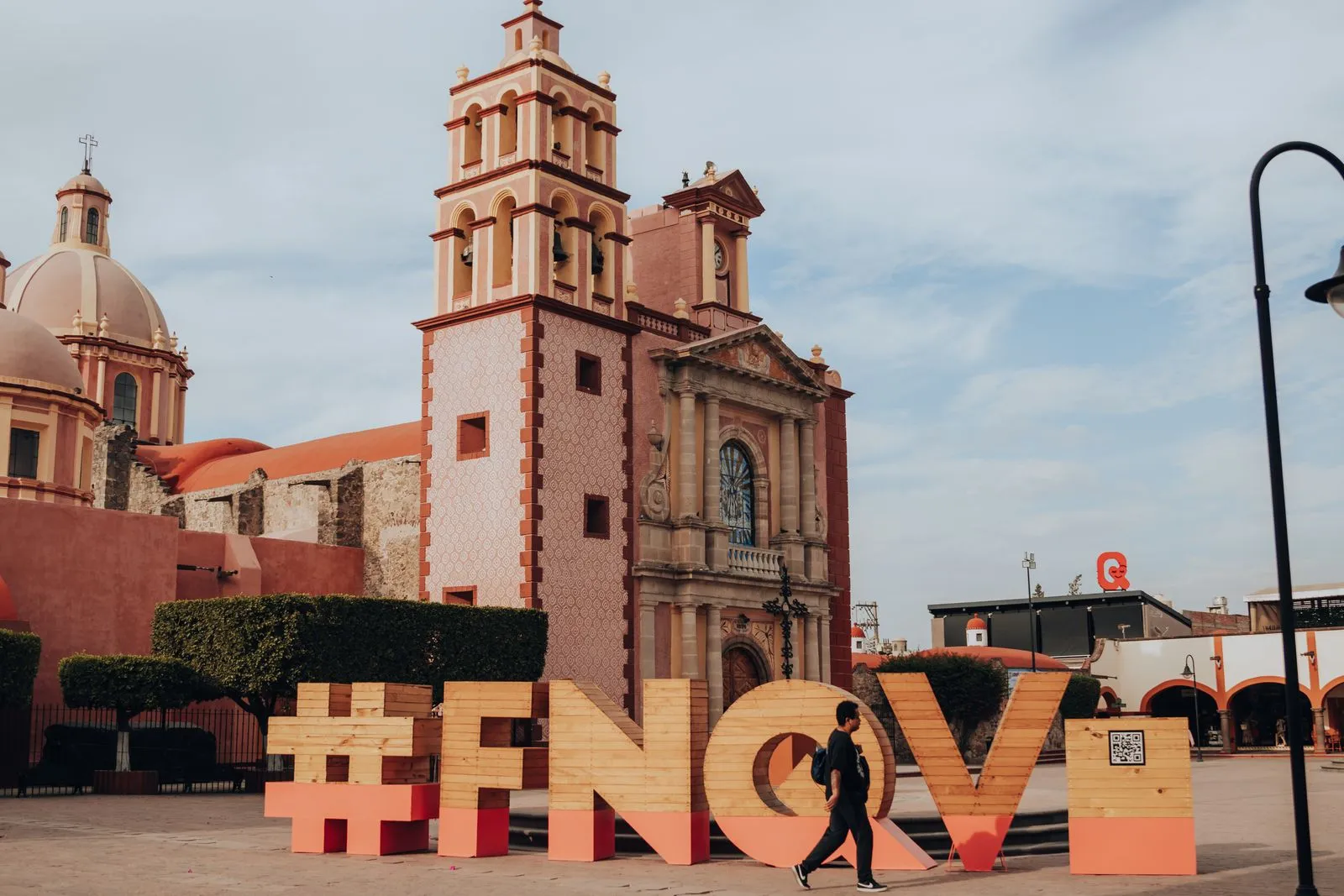Historic church and urban scene in Tequisquiapan, with a man walking by large decorative letters.