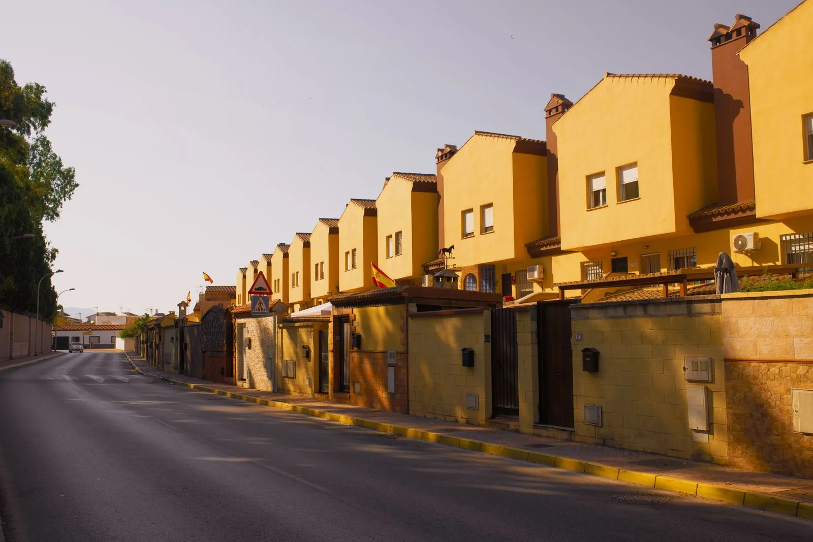 Row of yellow suburban houses under warm evening light, showcasing Mediterranean architecture.